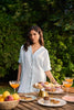 Woman standing behind a table with food and drinks outdoors
