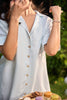 Woman enjoying a snack outdoors with a table of food and drinks in the background