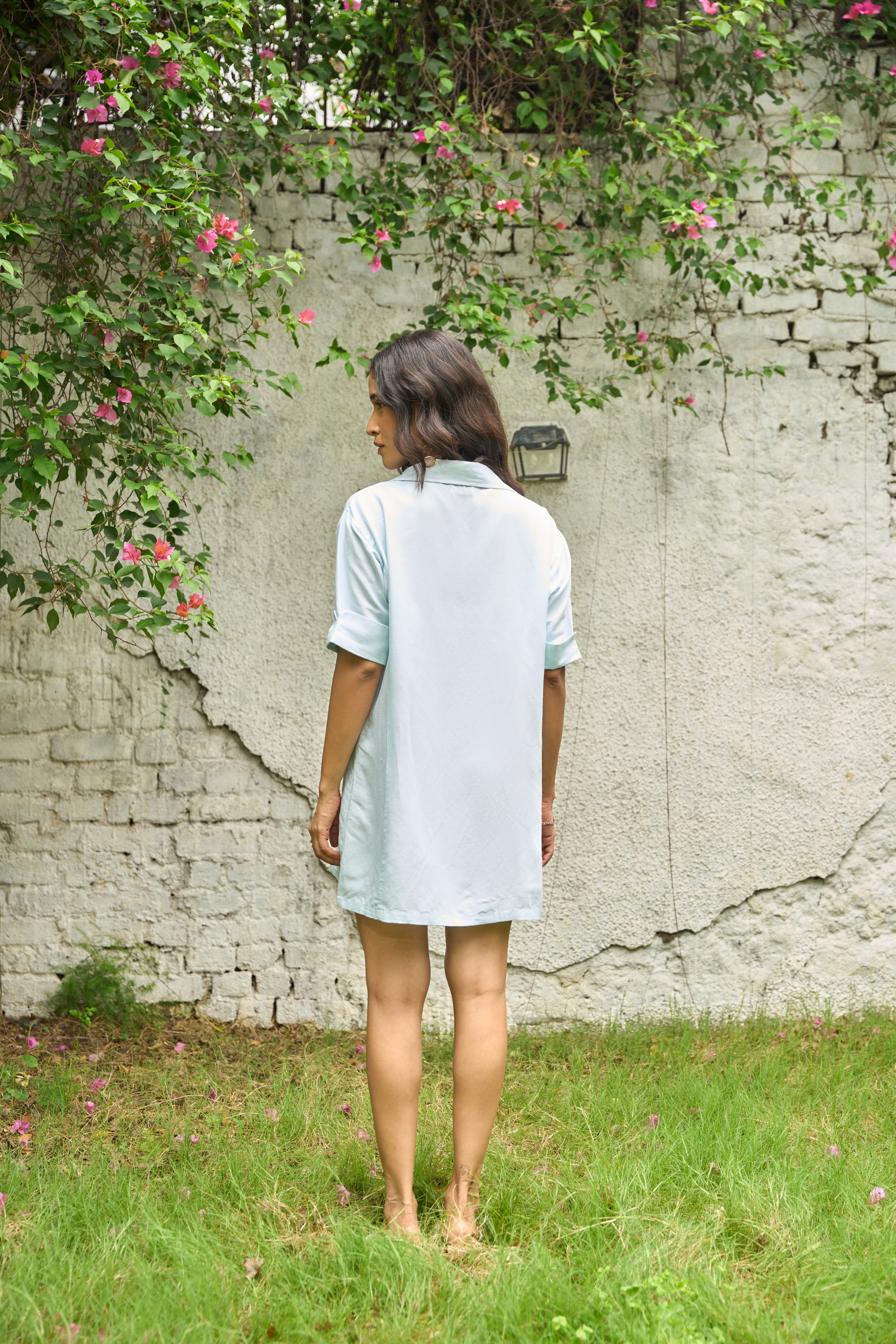 Woman standing in front of a textured wall with greenery