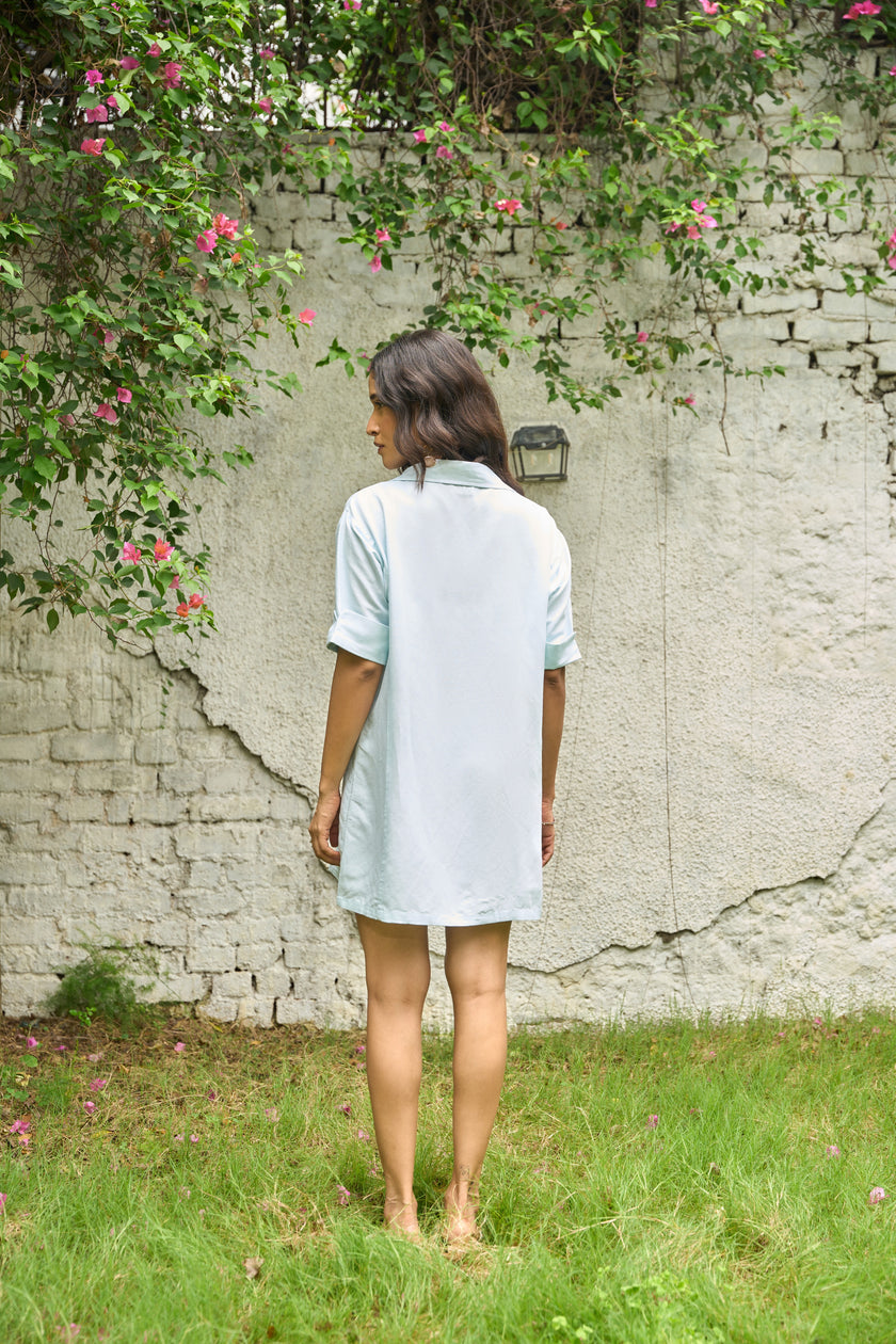 Woman standing in front of a textured wall with greenery